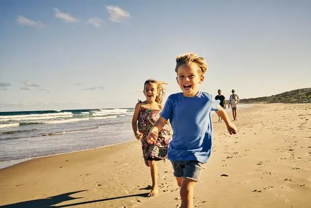 Children running and having fun on a beach. Image