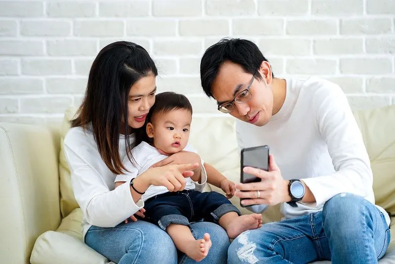 A mum and dad show their baby an educational video.