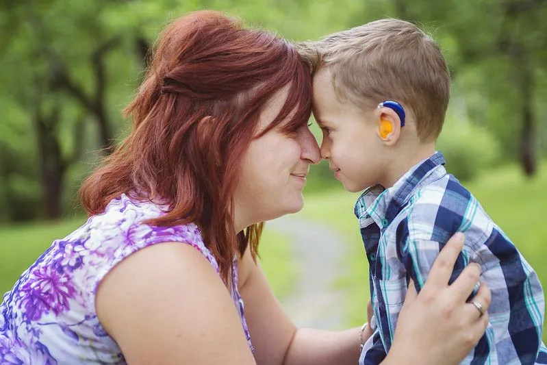 Mother touching heads with deaf child.