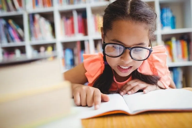 Girl reading an oxford reading tree book in her school library.