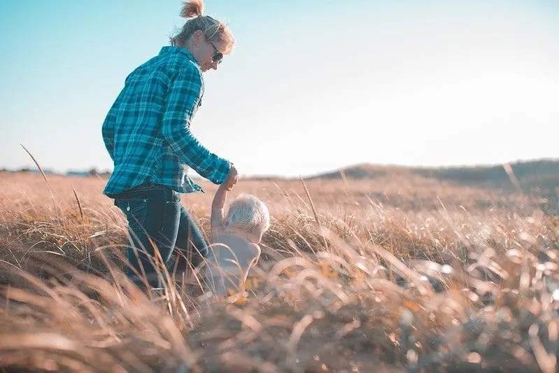 Mother and son walking across a field of wheat with a blue sky in the background