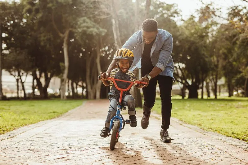 dad helping his son to ride a bike without stabilisers