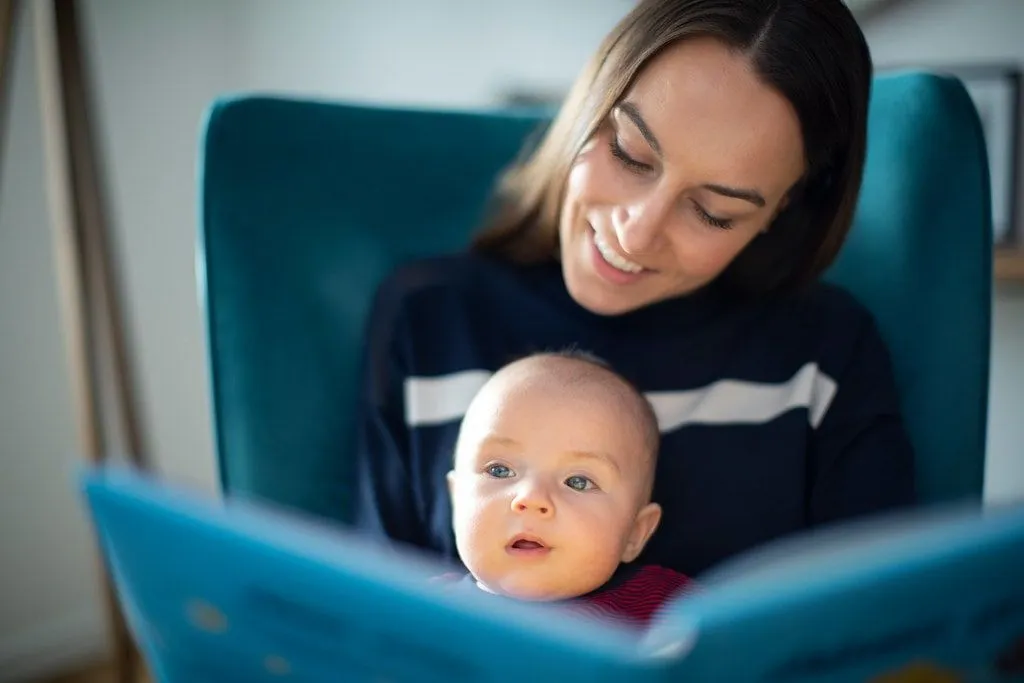 Mum reading a book to 1-year-old.