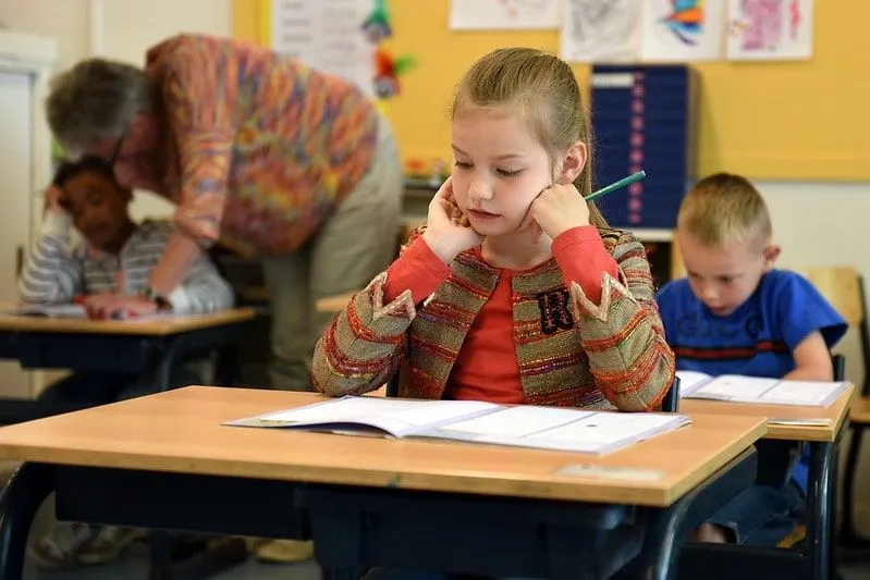 Young girl sat at her desk in the classroom sitting a test.