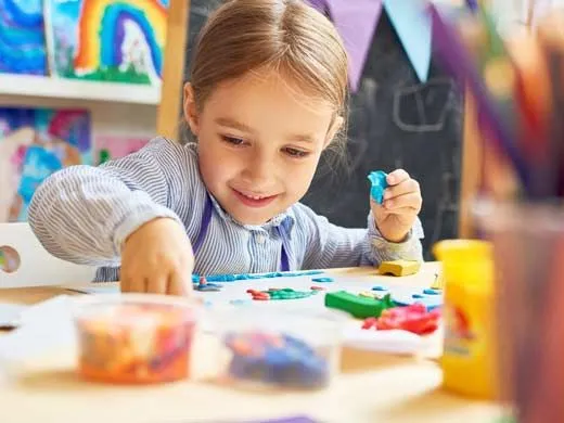 Little girl sat at the table doing fairytale arts and crafts.