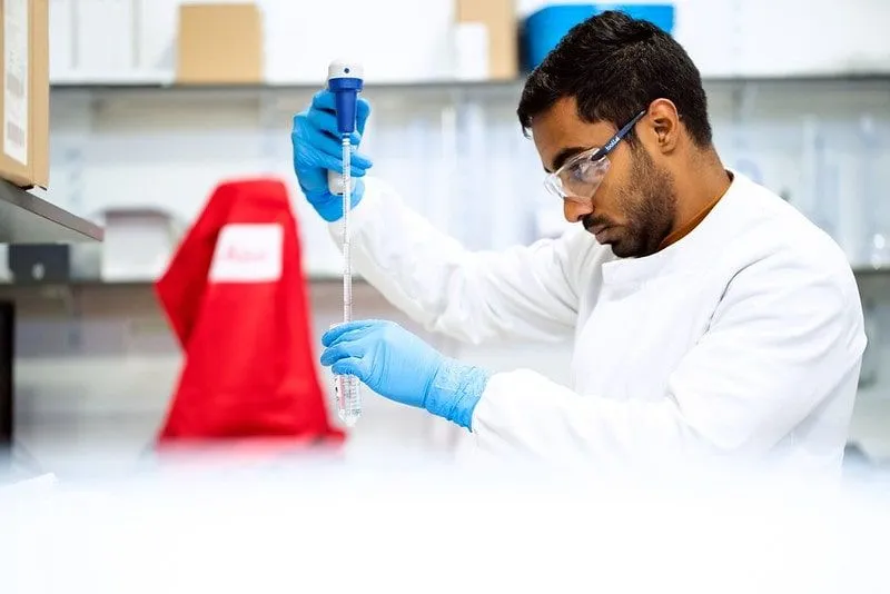 Scientist in a lab with a pippet and test tube testing mitochondria.