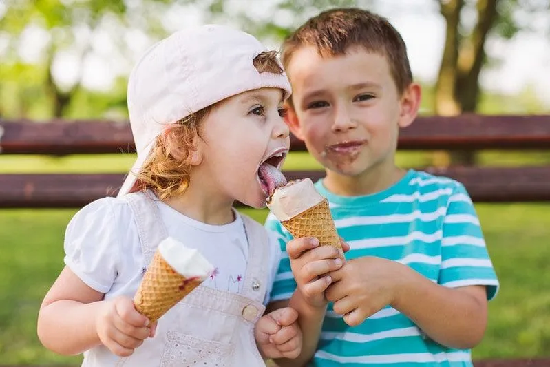 Brother and sister eating ice cream, the little girl's brother lets her have some of his.