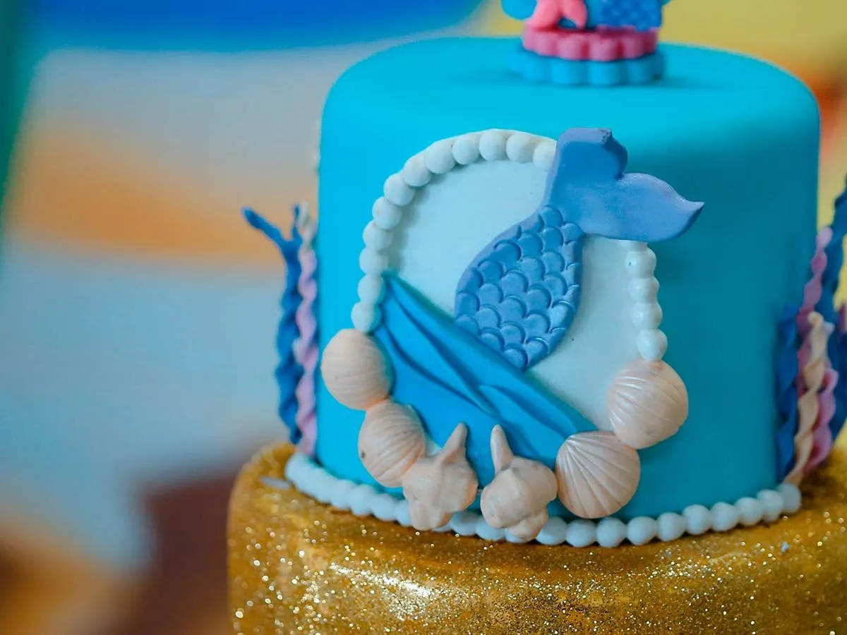 Under-water-themed cake with blue icing and a mermaid's tail on the side.