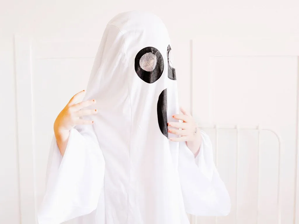 A child wearing a large white ghost costume.