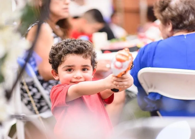 Boy in red shirt playing water gun in the park.