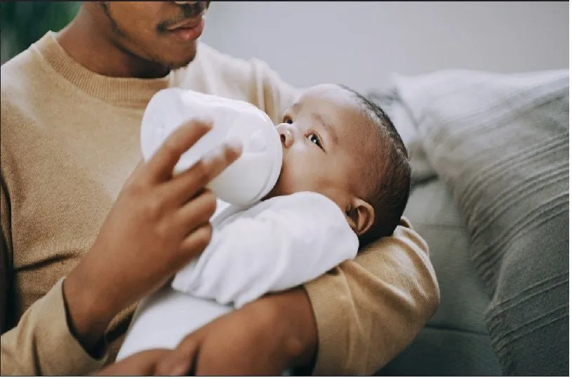 Father feeding baby in the bottle.