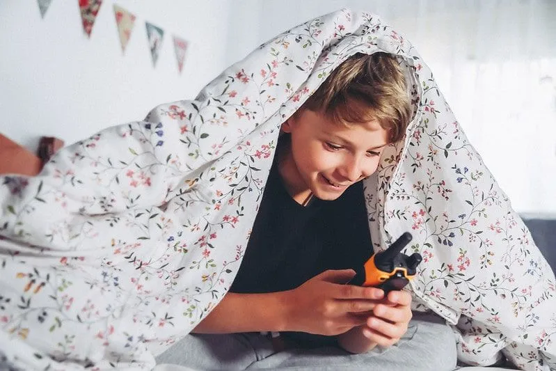 Kid under duvet playing. 