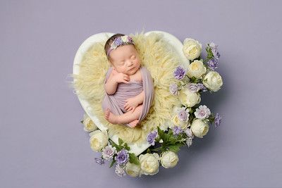 Newborn baby sleeping in a furry basket with white and lavender flowers - Nicknames