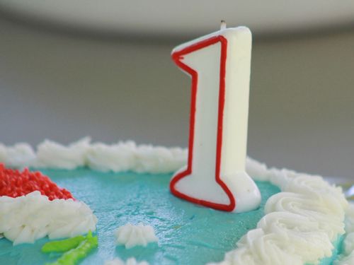 Number one candle on a blue birthday cake.
